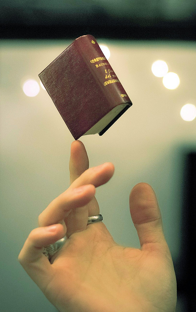A very small book being balanced on a man's finger